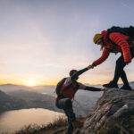 Young woman offers man a hand up, in the Swiss Alps